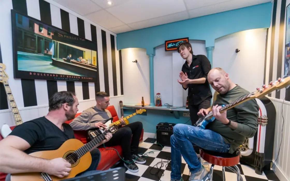 Coach geeft een deelnemer een spoedcursus op de gitaar