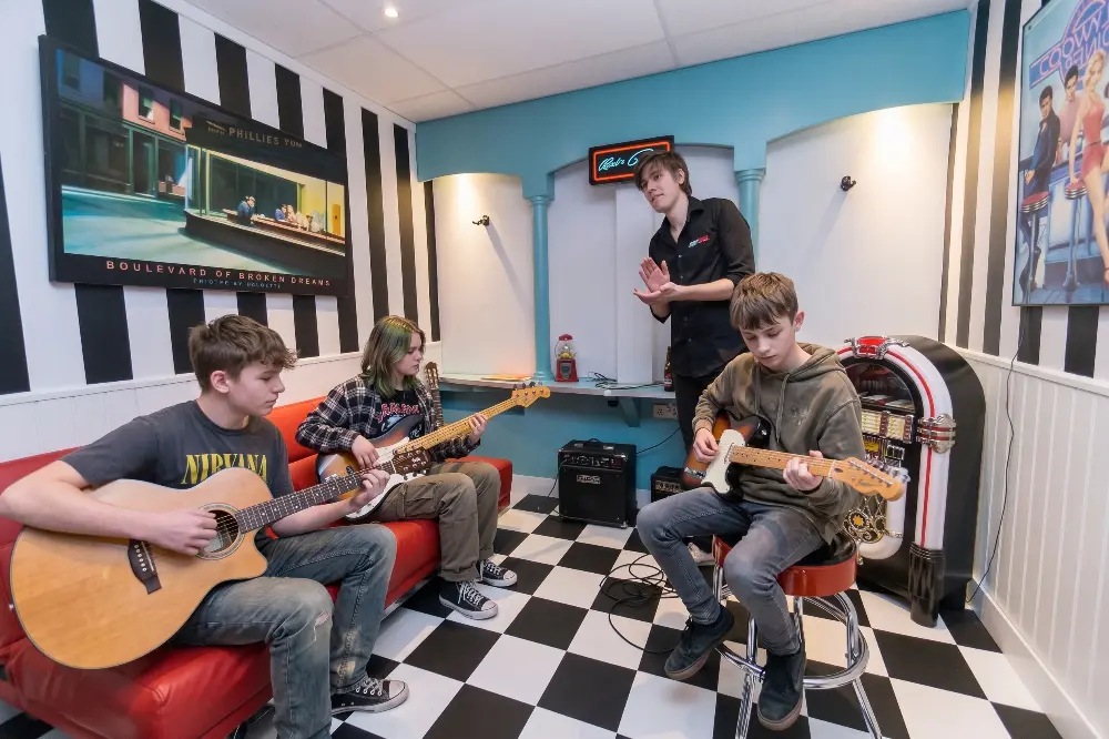 Een coach leert een beginner de eerste akkoorden op de gitaar