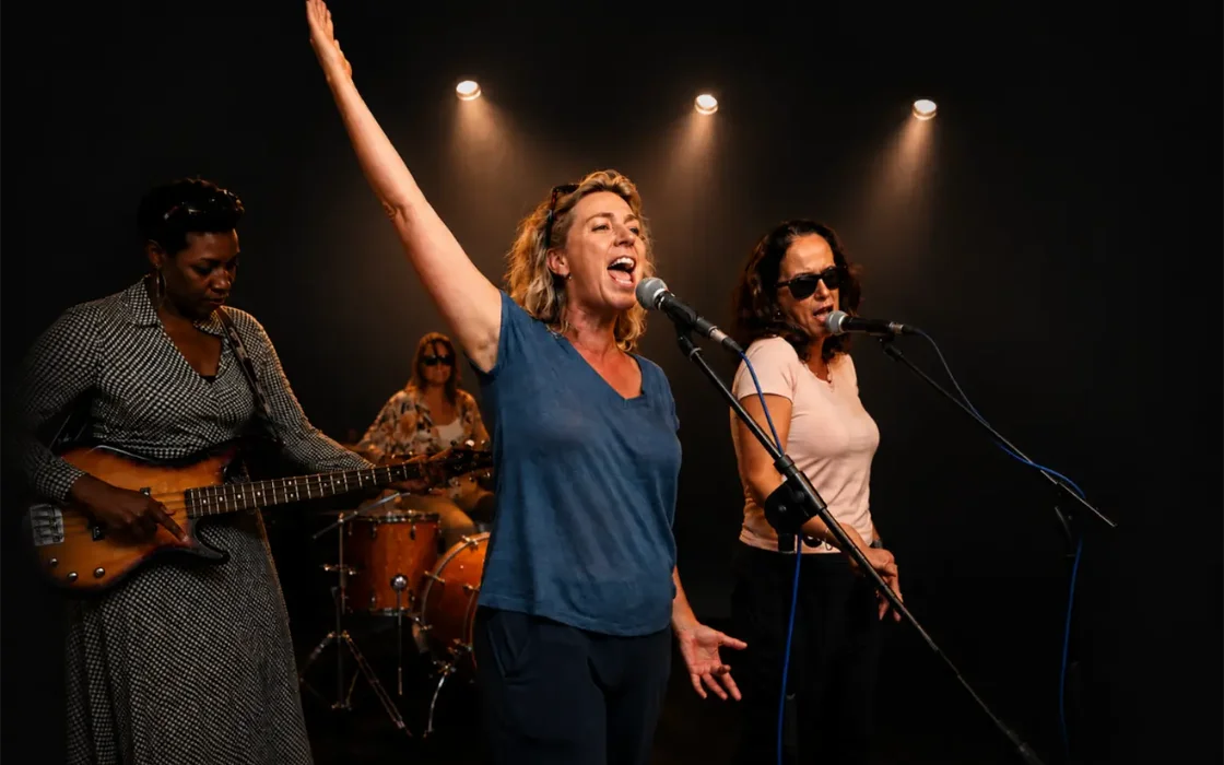 Vriendengroep repeteert samen als band, met een coach die de gitarist helpt