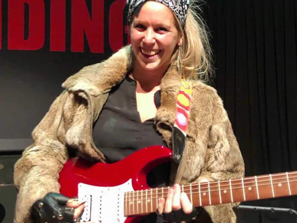 vrouw speelt gitaar tijdens bedrijfsuitje bij de gitaar workshop van teambanding